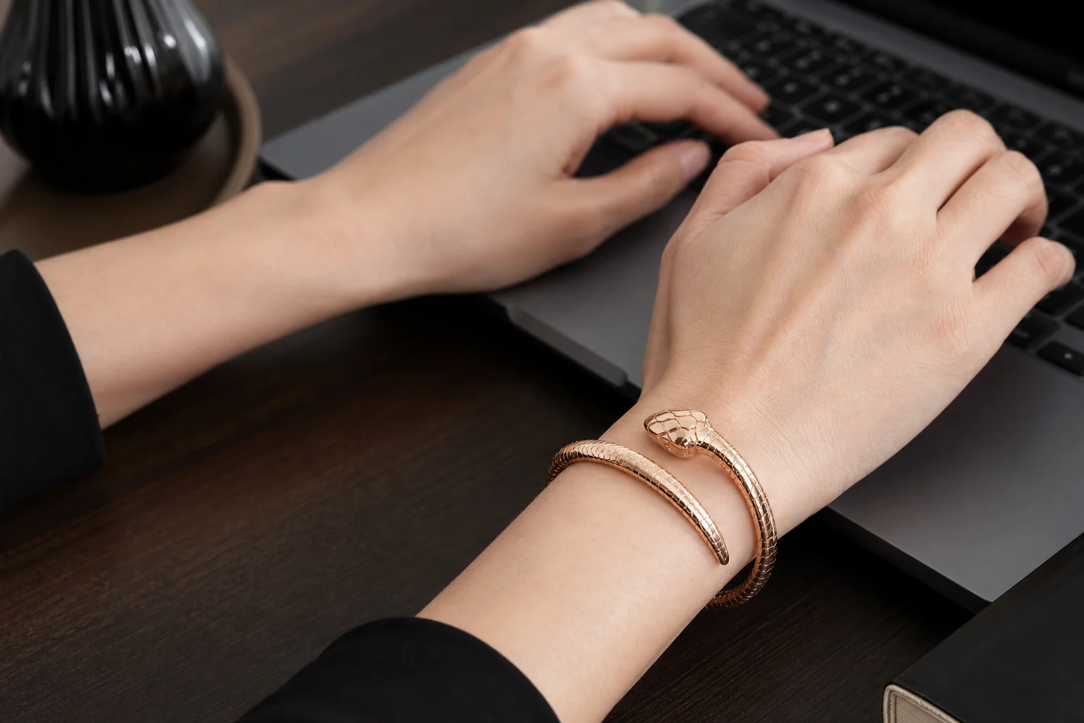 Serpent-inspired rose-gold bracelet worn while typing to demonstrate daily-wear fit and wrist movement