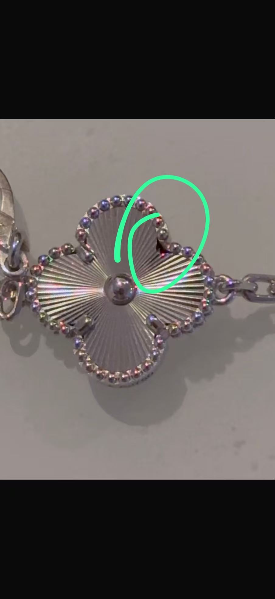 Guilloche clover motif with a green mark identifying the reported damaged retaining-prong area on a 12.5g bracelet