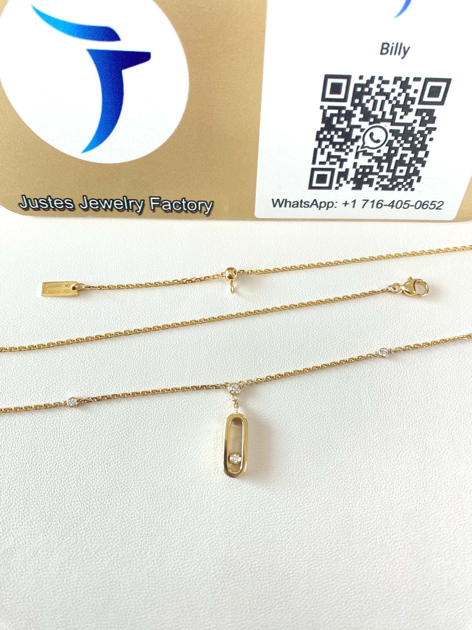 Move Uno style pendant necklace and chain displayed in front of the Justes logo and QR code sign
