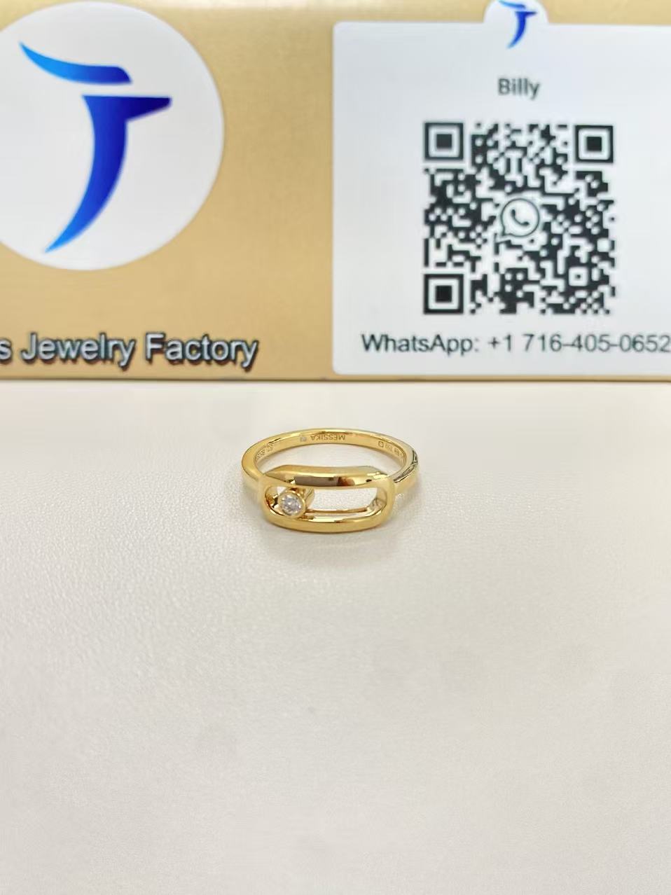 Move Uno style large ring in yellow gold displayed in front of a Justes logo and QR code sign
