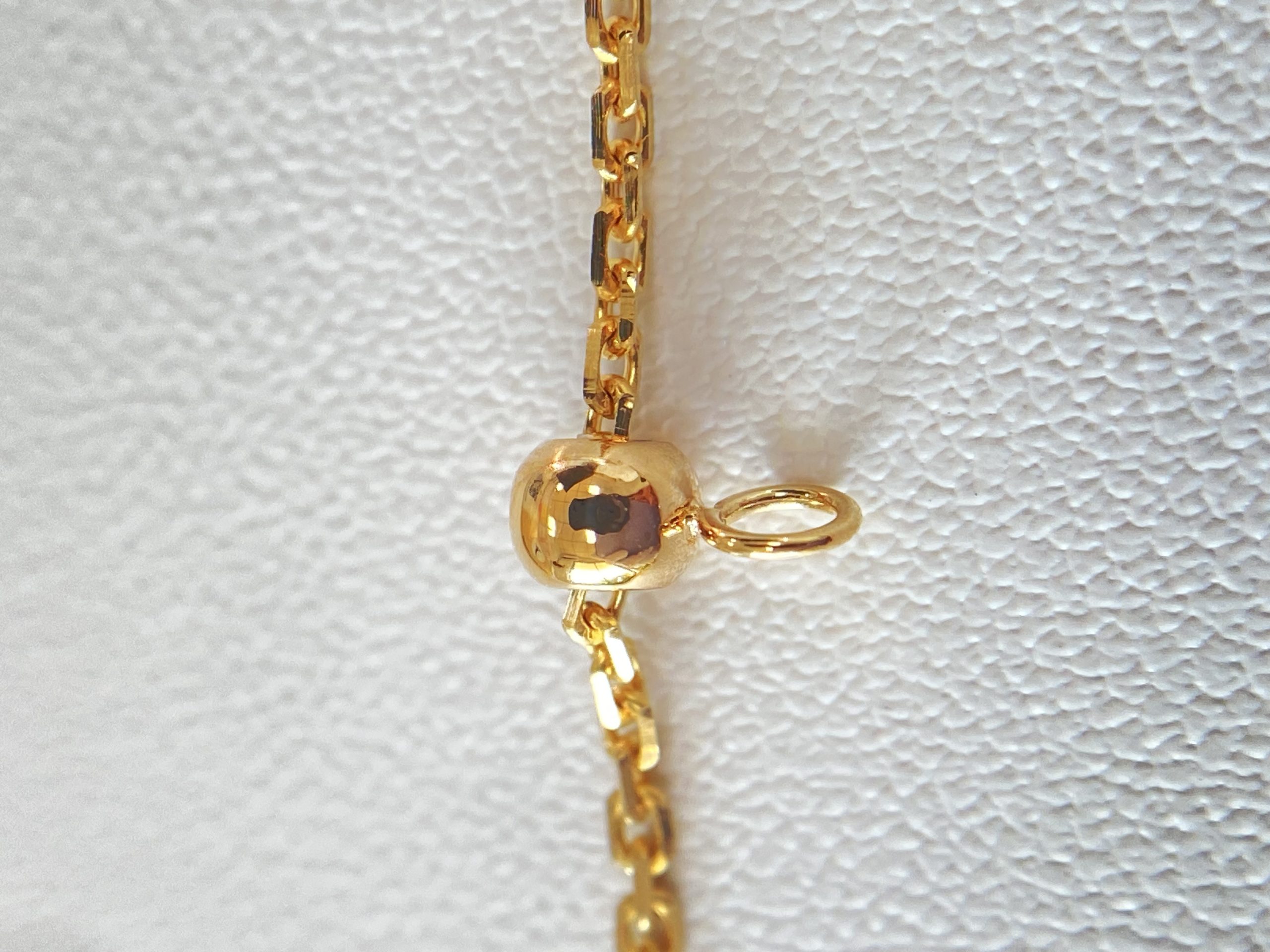 Sliding bead and chain adjustment detail on the yellow gold necklace