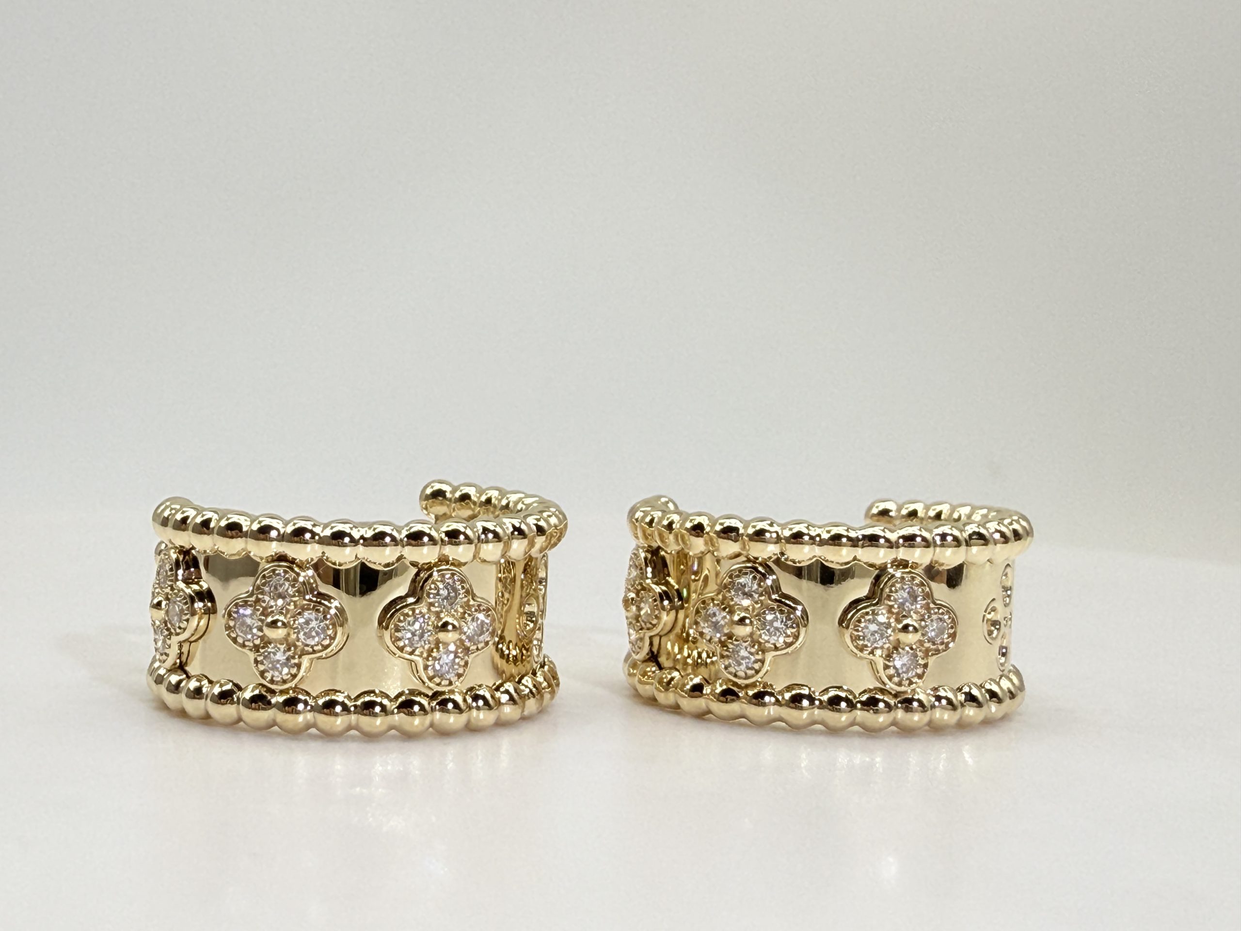 Front view of Justes clover-motif hoop earrings with rounded bead borders