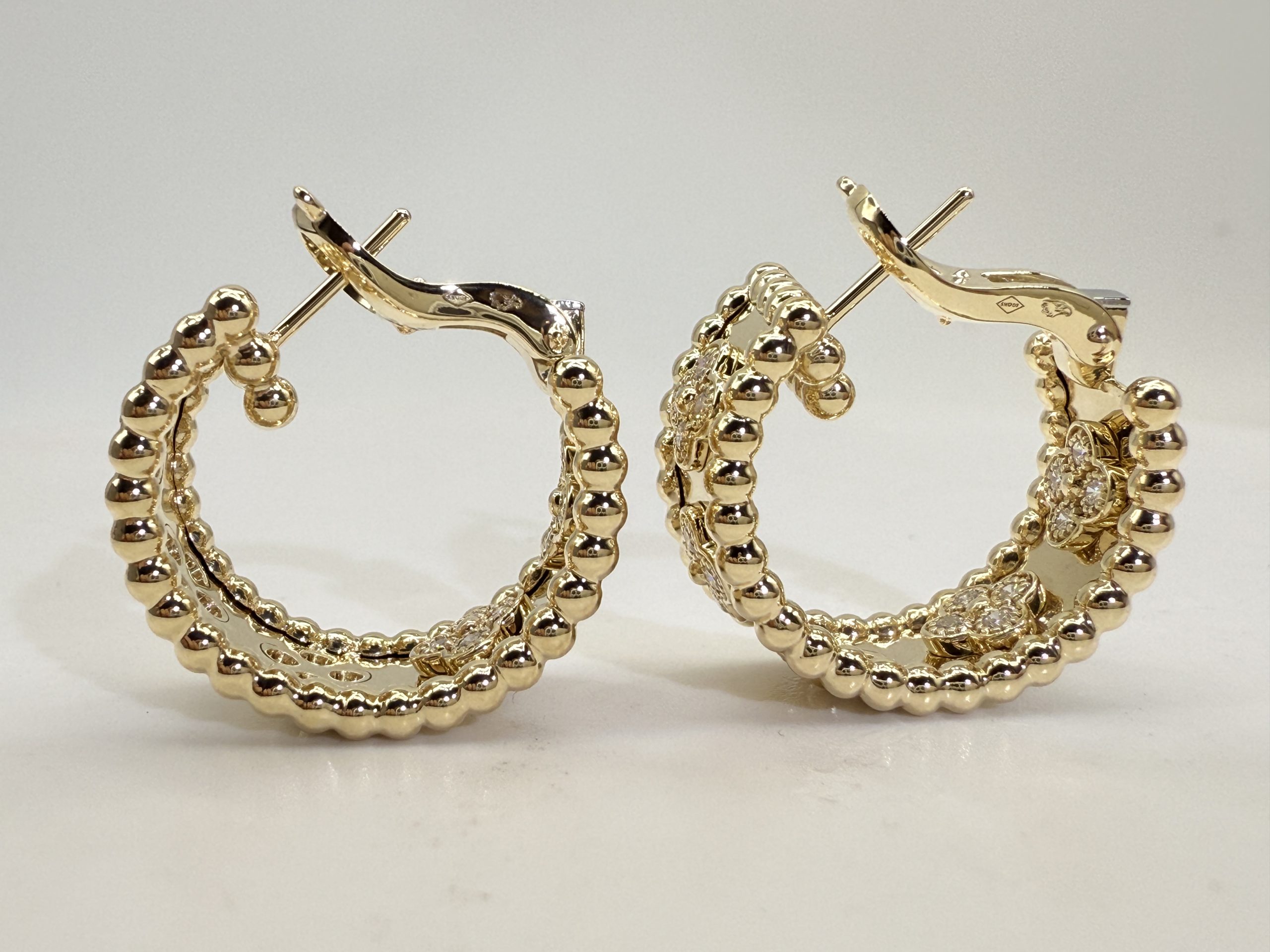 Angled view of Justes replica hoop earrings showing ear posts and open fastening arms